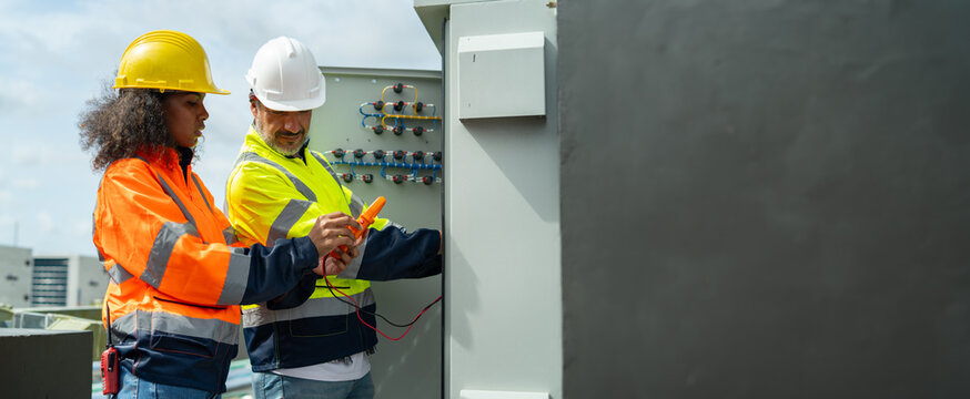 Electrician engineer man and worker woman dark skin wearing uniform  tester measuring voltage,skills quality,maintenance,training worker,Workshop for factory operators,Electrician engineering team.