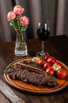 Grilled meat T-bone on the grill, cherry tomatoes lie on a wooden board. Serving food in a restaurant. background image