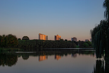 Fototapeta premium Lake in the city park. Sunset in a city park by the river. reflection of buildings in water