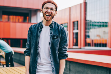 Half length portrait of cheerful caucasian male student laughing standing in college campus