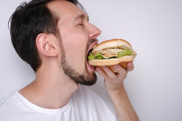 Portrait of a Caucasian man eating a burger on a white background side view