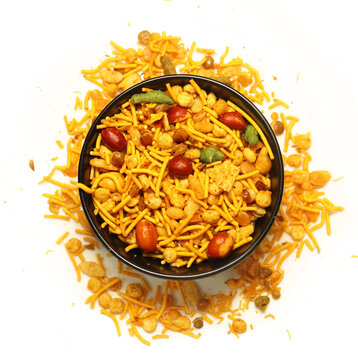 Close-up of Navratan Indian namkeen (snacks) on a ceramic black bowl. Isolated on white background. Top view
