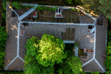 Aerial view of the leaky roof of an abandoned decaying building in a forest area
