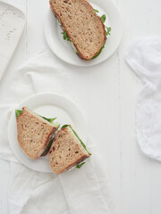 Veggie sandwiches served on plates on a white wooden table with space for text.