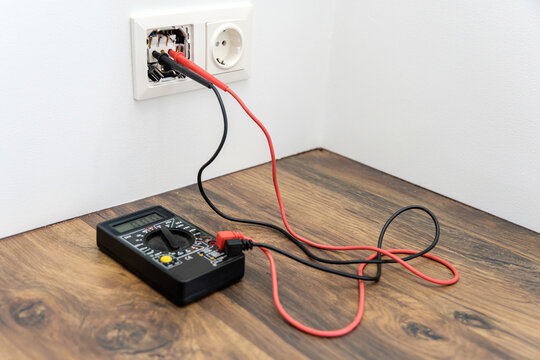 a pair of wire probes are plugged into the socket. Multimeter for measuring voltage.