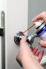 master using lubricant in a spray can for a door handle. Repair and installation concept