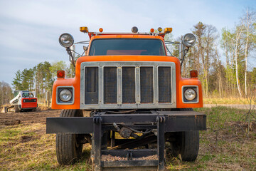 Close view of the front of an orange truck at construction site.