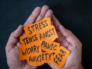 Hands hold pieces of paper with words worry, stress panic and anxiety.