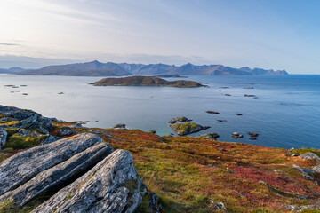 panoramic view over the autumnal colored nature from the island of Kvaløya, Norway, with many wind turbines. red and orange colored plants between green and yellow grass over atlantic ocean © Dieter
