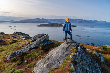 hiking woman on hill, autumnal nature of Norway. Hiking by the fjord and mountains on the island of...