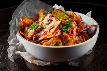 plate of delicious tortilla nachos with melted cheese sauce, ground beef, jalapeno peppers in bowl