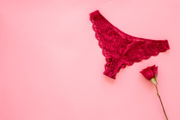 Elegant red lace lingerie bikini panties with red rose, top view - obrazy, fototapety, plakaty