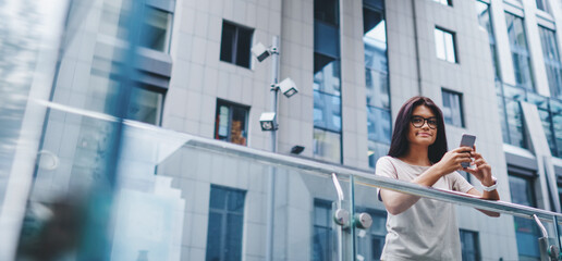 hipster girl using internet connection in roaming on cellphone looking at camera on street