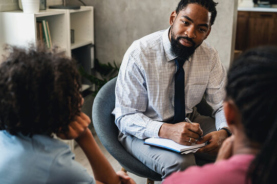 African American woman with teen son have a meeting with a psychologist. A psychotherapist session with a patient. mother seeks professional help for her teenage son - Powered by Adobe
