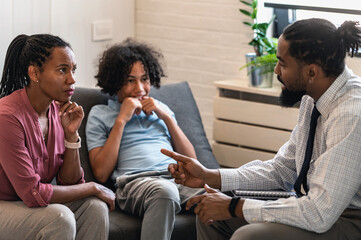 African American woman with teen son have a meeting with a psychologist. A psychotherapist session with a patient. mother seeks professional help for her teenage son - obrazy, fototapety, plakaty