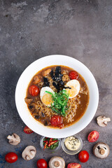 ramen in a white plate on a background with vegetables top view