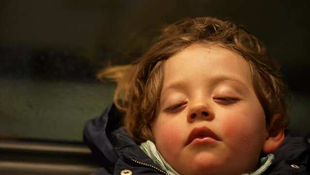 One small boy asleep on moving train. Closeup child face sleeping in transportation. Cute kid napping