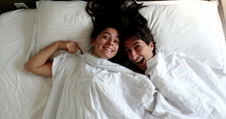 Fun couple under blanket laughing and playing hide and seek peekaboo