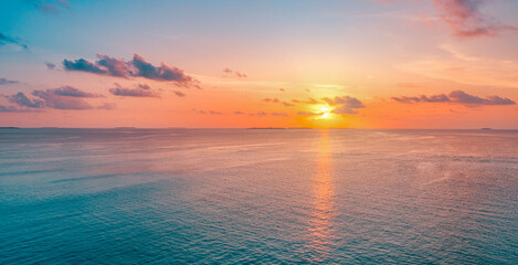 Aerial panoramic view of sunset over ocean. Colorful sky clouds water. Beautiful serene scene, wide...