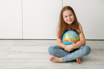 happy girl hugging the globe while sitting on the floor cross-legged