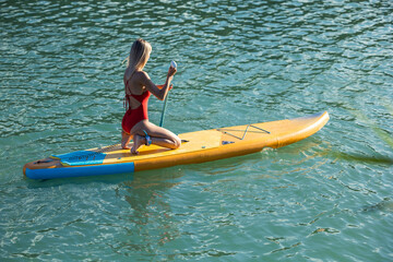 Woman paddling on sup board in blue ocean.