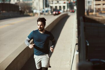 Young and athletic caucasian man jogging on a bridge in the city