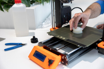 Modern 3D printer equipment and man working with it in office.