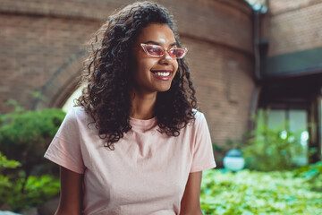 happy cheerful dark skinned woman in stylish sunglasses enjoying leisure outdoors