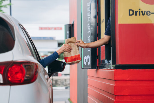 Young Man receiving coffee at drive thru counter., Drive thru and take away for protect covid19.
