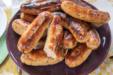 Grilled barbecue sausages on a plate, top view, close-up
