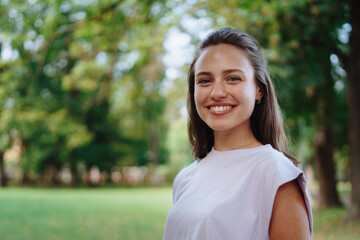 Portrait of a beautiful young woman standing outside in a city park, with copy space.