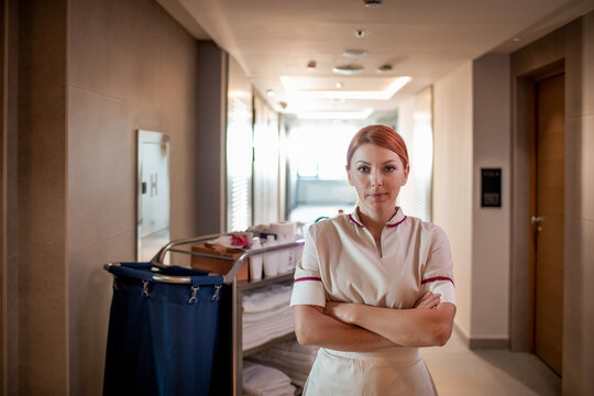 Portrait of a confident young cleaning lady posing in the hotel hallway