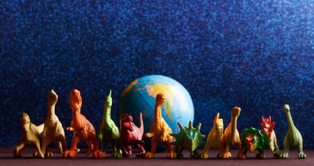 Toy dinosaurs protect the globe on a shimmering blue background. Concept of protecting planet Earth...