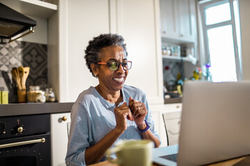 Senior African American woman using a laptop in the kitchen in her home