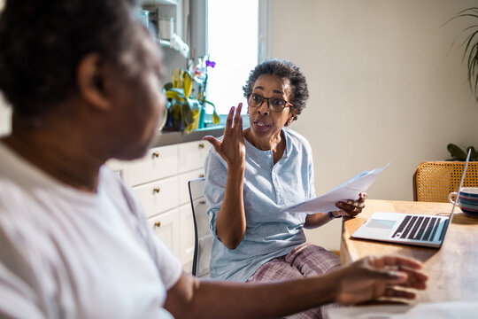Senior African American woman going over bills and payments with her husband in the kitchen at home