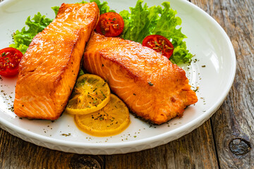 Seared salmon steaks with lettuce and lemons on wooden table
