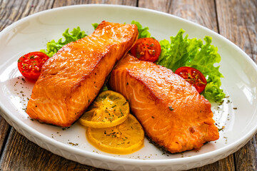 Seared salmon steaks with lettuce and lemons on wooden table

