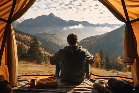 A man enjoys the view of the autumn mountains while looking outside of his tent Generative Ai