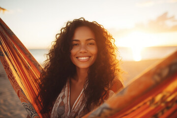 Mixed race woman on beach holiday lying in hammock reading book during sunset - Powered by Adobe