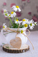 Daisies in white jug and wooden heart