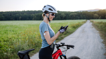 Diabetic cyclist with continuous glucose monitor checking on smartphone smartphone her blood sugar...