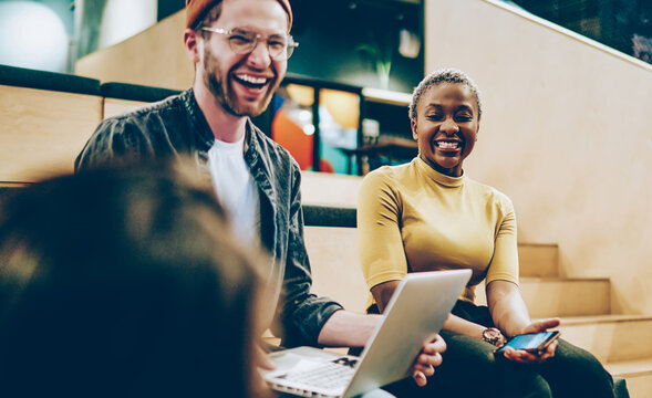 overjoyed crew of diversity hipster colleagues laughing at jokes while share ideas for job