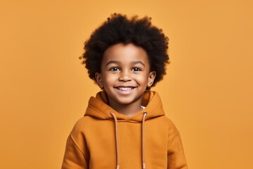 Obraz na płótnie Canvas Studio Photography of a black 6 year Boy in an orange hoodie smiling at the Camera in front of an orange background Genertive Ai