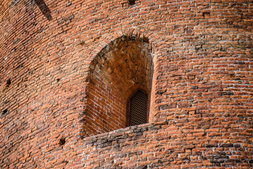 Window in the wall of an old red brick defensive watchtower