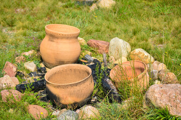 Old red clay pots lie in an extinguished fire with black coals