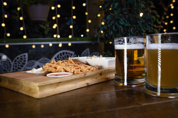 Beer and snack onion rings on wooden table.