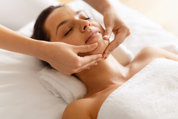 Fototapeta na wymiar Closeup Of Peaceful Attractive Woman Enjoying Facial Massage Indoor