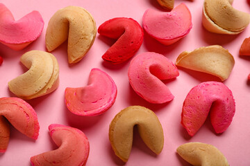 Many different fortune cookies scattered on pink background