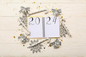 Notebook with written numbers 2024 and beautiful Christmas decorations on white wooden background