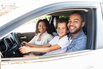 Cute african american family posing inside brand new car